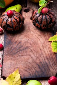 Jack-o-lantern around empty cutting board on wooden background. Autumn concep Stock Photos