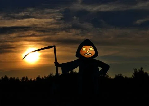 Jack-o-lantern in a black cloak and with an iron scythe Stock Photos