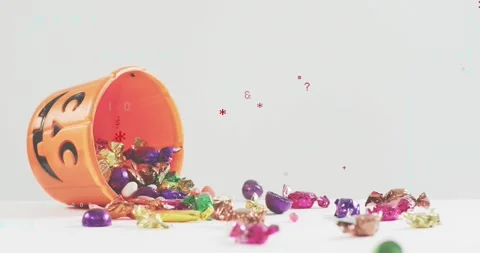 Jack-o'-lantern bucket dropping onto tabletop, spilling candies, transforming Stock Footage 317791804