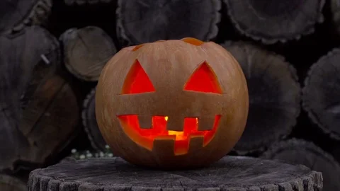 Jack-o-lantern with fire inside flickers lying on a stump Stock Footage