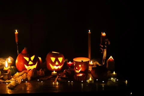 Jack o lantern glowing pumpkins, spooky spiders and burning candles on dark Photos