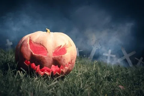 Jack-o-lantern in a graveyard at night Stock Photos