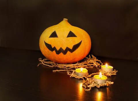 Jack-o-lantern pumpkin with face made by children next to burning candles Foto stock