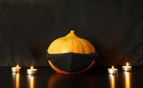 Jack-o-lantern pumpkin with face drawn on black protective mask Stock Photos