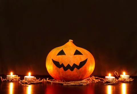 Jack-o-lantern pumpkin with face made by children next to burning candles Stock Photos