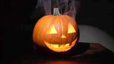 Jack o lantern pumpkin lit up with smoke emanating from face Stock Footage 141547310