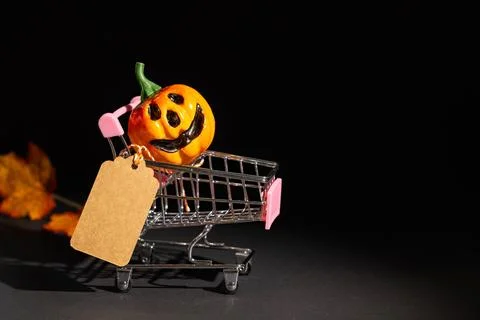 Jack-o-lantern riding in miniature shopping cart with blank tag for Hallowe.. Stockfoto's