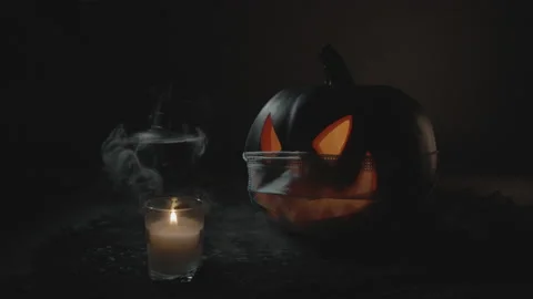 Jack-O-Lantern wearing Face Mask next to Steaming Cauldron with lid ajar Slow-Mo Stock Footage 138183993