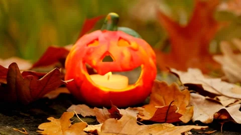 Jack pumpkin lantern with a lit candle and slowly falling autumn leaves. Stock Footage 204030382
