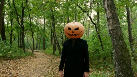 Jack Pumpkinhead is standing in the forest, Guy puts a real pumpkin on his head. Stock Footage 116500344