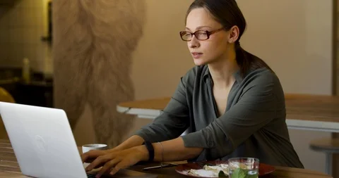  jacket and stylish glasses sitting in cafe, talking on the phone and looking at Stock Footage 126698771