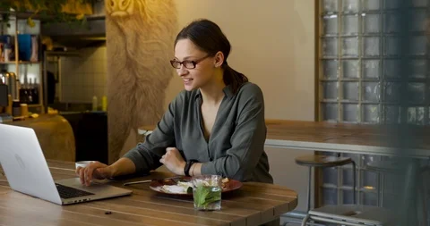  jacket and stylish glasses sitting in cafe, talking on the phone and looking at Stock Footage 126698800