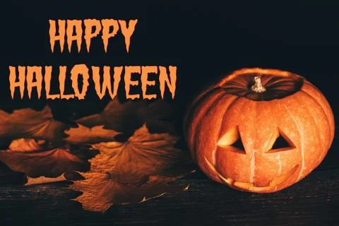 Jack's pumpkin lantern on a black background with maple leaves Stock Photos