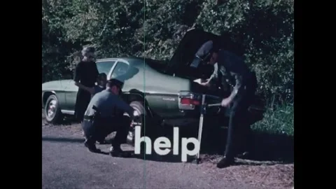 JACKSON - 1970s - Policemen using car jack to lift a car with a flat tire. They Stock Footage 341985561