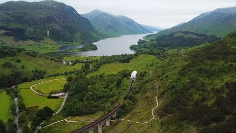 Jacobite steam train travelling through Scottish Highlands, aerial follow Stock Footage