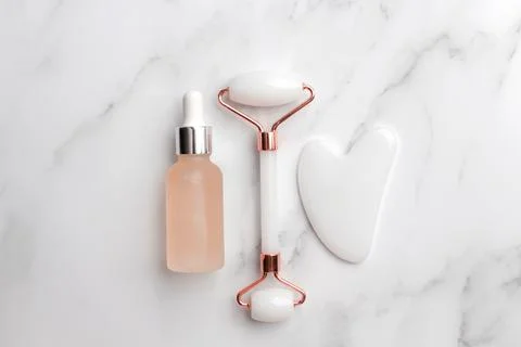Jade face roller and Gua sha stone for facial massage. Stock Photos