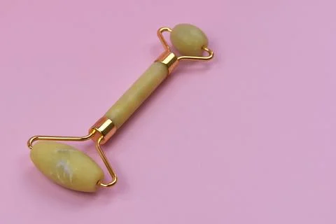 Jade face roller on a pink background. Face massage tool. Stock Photos