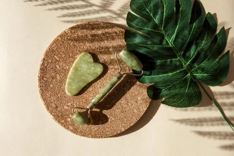 Jade Gua sha scraper and face roller massager on a cork round stand with a mo Stock Photos