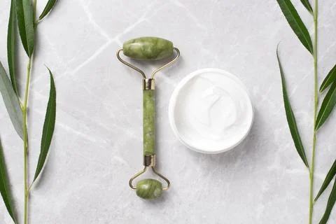 Jade roller for face massage. Container with bodycare and skincare cream. Foto stock