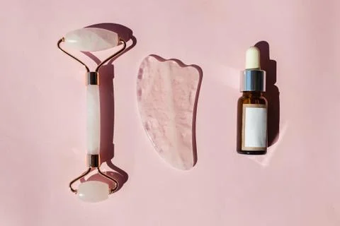 Jade roller, gua sha tool and bottle of skin serum. Stock Photos