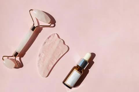 Jade roller, gua sha tool and bottle of skin serum. Stock Photos