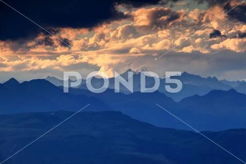 Jagged blue silhouettes and orange clouds High Tauern Austria Stock Photos