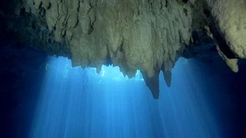 Jagged limestone ceiling framing blue cenote sunbeams Stock Footage 341395856