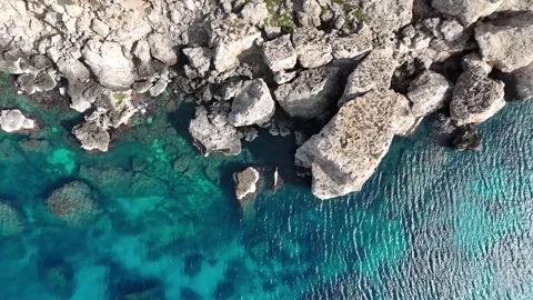 Jagged limestone rock outcrops malta turquoise sea reef patterns birds eye drone Stock Footage 343594243