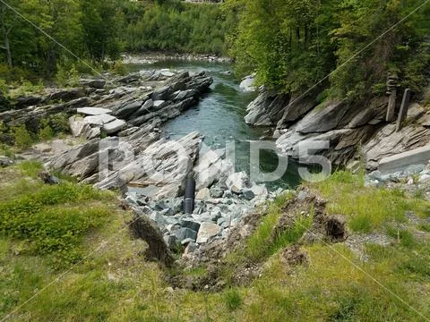 Jagged rocks and water in stream or river and discharge pipe Stock Photos