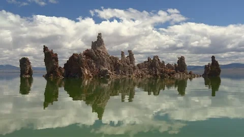 Jagged tufa towers with sharp vertical shapes reflected on the still green Stock Footage 328470860