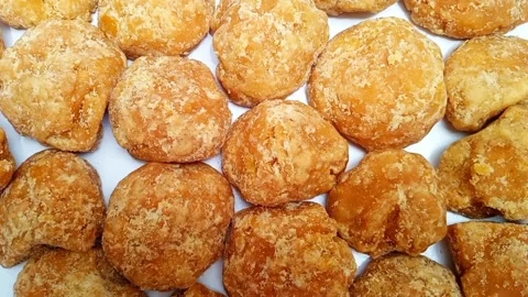 Jaggery or Gur pieces texture background rotating on white, top view. sugar cane Stock Footage 282583876
