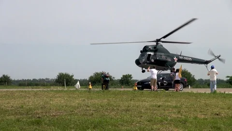 Jaguar car at start. Mi-2 helicopter lands next to Jaguar. Stock Footage 121203542