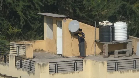 Jaipur - Man fixing satellite dish antenna at home rooftop on a sunny day Video stock 197003399