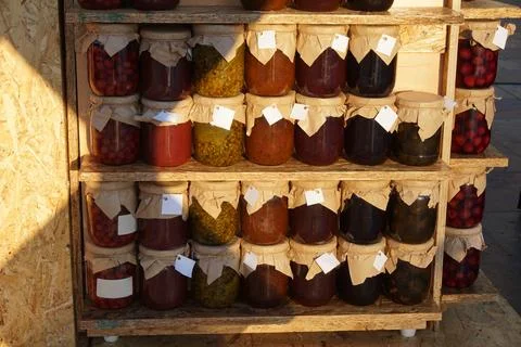 Jam and compote Jars with paper wrapped lid in wooden shelves in Green Fest. Stock Photos