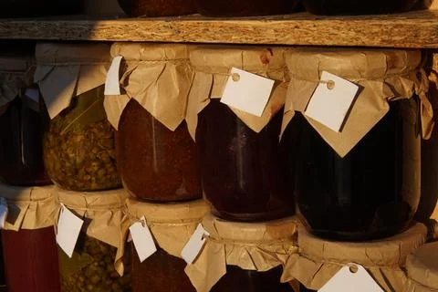 Jam and compote Jars with paper wrapped lid in wooden shelves in Green Fest. Stock Photos