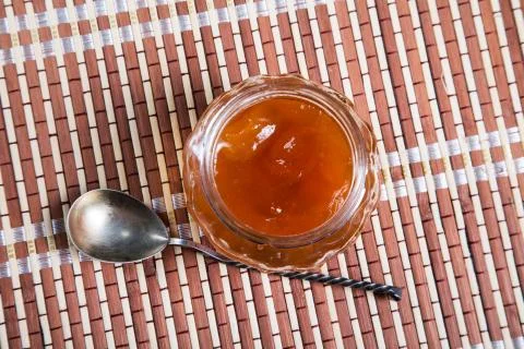 Jam jar with a spoon on a close-up table Stock Photos