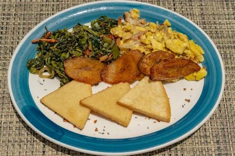 Jamaican breakfast of bammy, plantain, ackee and sailfish, and callaloo Stock Photos