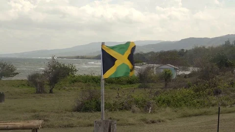 Jamaican flag on a windy day. Beautiful Caribbean sea in the background. 4K.. Stock Footage