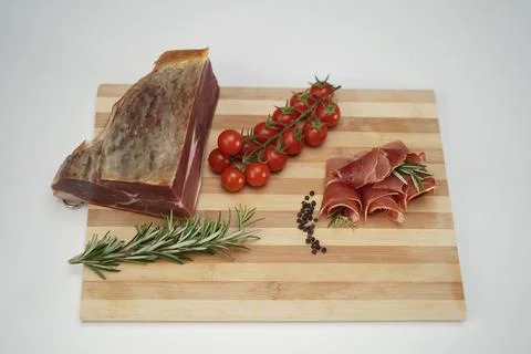 Jamon with cherry tomatoes on a wooden kitchen board 写真素材