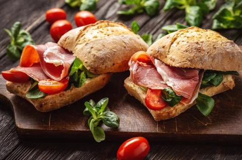 Jamon sandwiches with tomatoes, on wooden board. Stock Photos