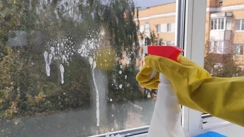 Janitor hand in protective glove spraying cleaning solution on window surfa.. Stock Footage 346784775