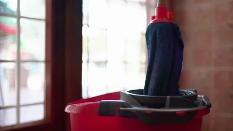 Janitor soaking mop inside the bucket with warm water and disinfection detergent Stock Footage 203838126