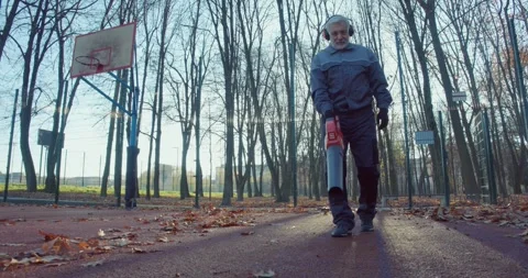 Janitor using leaf blower for cleaning autumn park Stock Footage 249318571