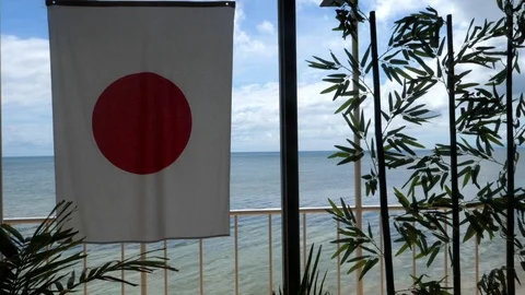 Japan flag hanging in front of the ocean in restaurant Stock Footage 86594342