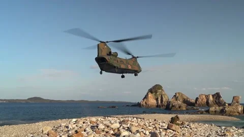 Japan Self Defence Force CH-47JA Chinook helicopter takes off from pebble beach Stock Footage 221554689