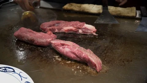 Japanese chef adding oil into beef on the sizzling hot pan cooked Stock Footage 84920165