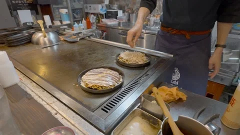 Japanese chef applying fish flakes to an Okonomiyaki pancake, Slowed to Stock Footage 245409977