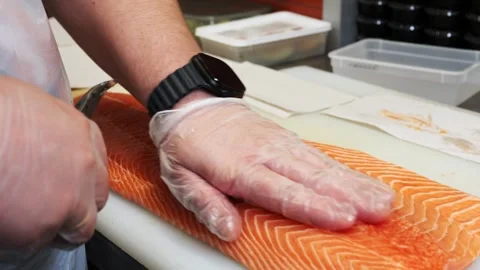 A Japanese chef in gloves carefully pulls bones from a large salmon with tongs Stockbeeldmateriaal 285372162