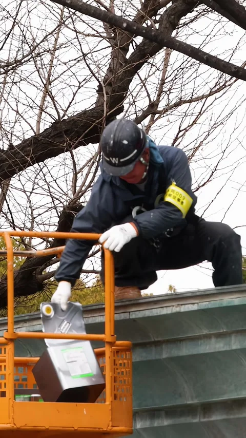 Japanese Construction Worker Performing Maintenance on Roof from Aerial Lift Stock Footage 338041860