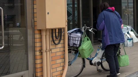Japanese Delivery Worker Loading Electric Bicycle on Tokyo Sidewalk Stock Footage 343609562